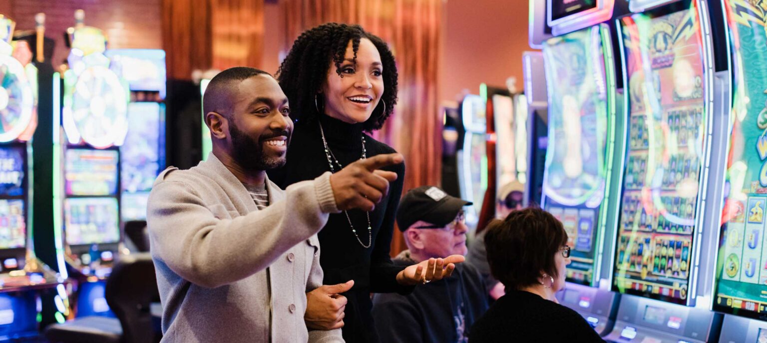 A couple pointing at something in the distance at a casino with a smile on their faces